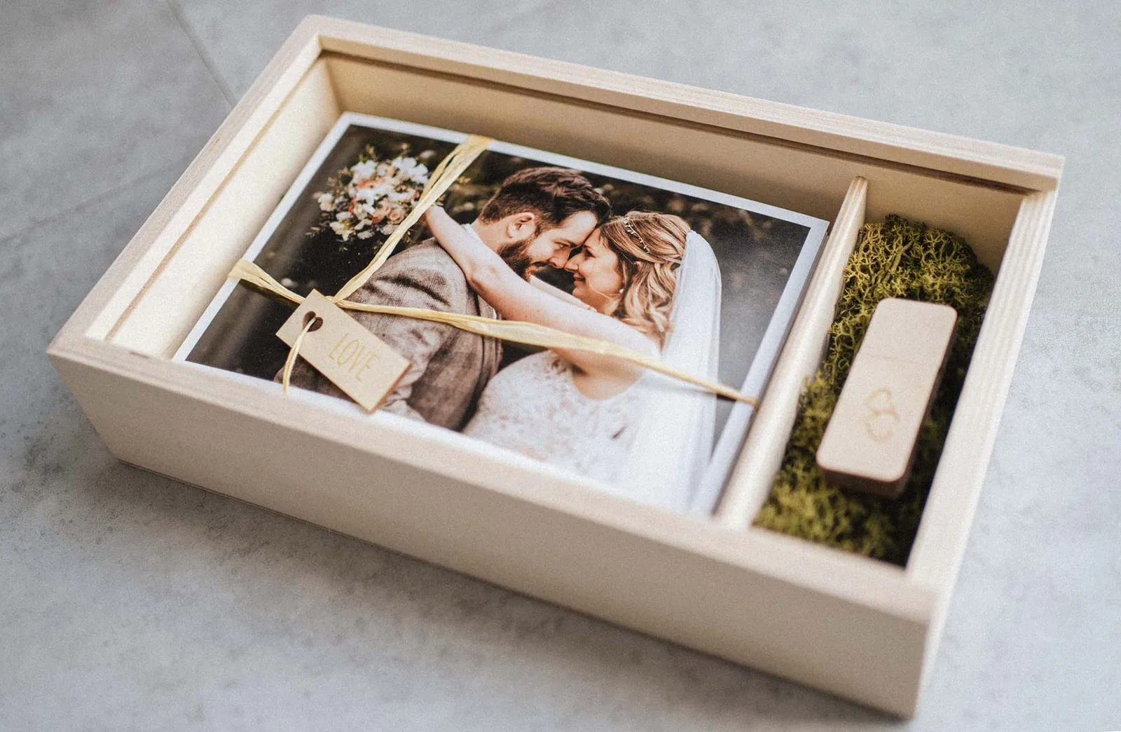 Geöffnete Holzbox mit Abzügen und USB-Stick – so kommen die Hochzeitsbilder an